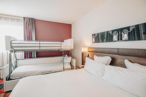 two beds in a room with two bunk beds at Holiday Inn Mulhouse by IHG in Mulhouse