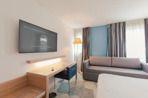 a hotel room with a couch and a tv at Holiday Inn Mulhouse by IHG in Mulhouse