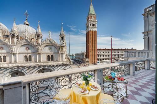 einen Tisch und Stühle auf einem Balkon mit einem Uhrturm in der Unterkunft Due Leoni Terrace In St Mark's Square in Venedig