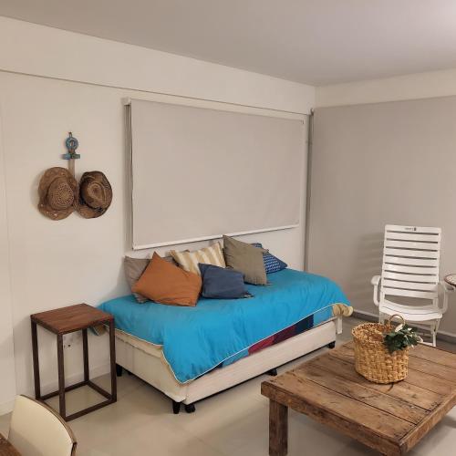 a bedroom with a bed with blue sheets and a table at Departamento Miranda in Villa Gesell