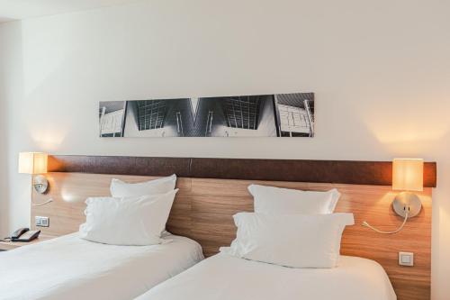 two beds with white pillows in a hotel room at Holiday Inn Mulhouse by IHG in Mulhouse