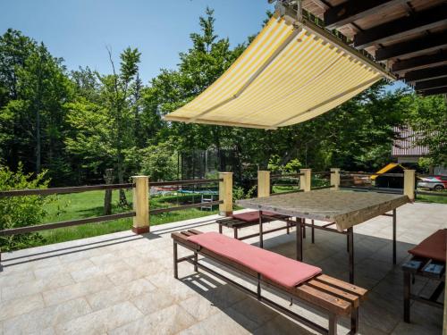 um pátio com uma mesa e bancos e um guarda-chuva grande em Holiday Home Legendao by Interhome em Lukovo