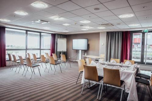 a conference room with tables and chairs and a projection screen at Holiday Inn Mulhouse by IHG in Mulhouse