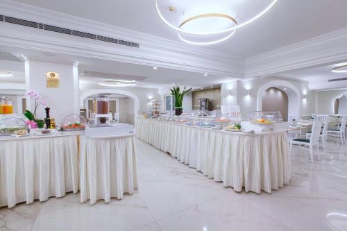 un restaurant avec des tables blanches et de la nourriture dans l'établissement Hotel Michelangelo, à Sorrente