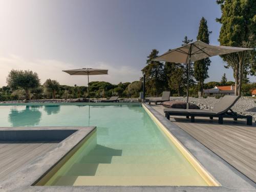 a swimming pool with two chairs and umbrellas at Holiday Home Quinta de Santa Emilia 3 by Interhome in São Martinho