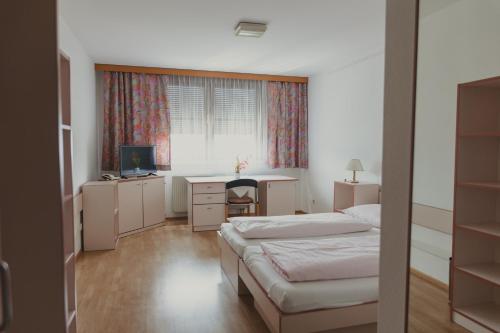 a bedroom with two beds and a desk and a window at Sommerhotel Karwendel in Innsbruck