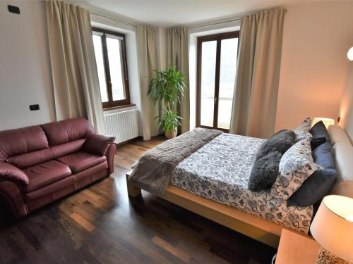 a bedroom with a bed and a couch and windows at Apartment Valley View Pool Apartment by Interhome in Ardenno