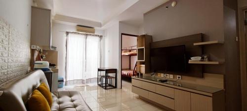 West Jakarta Urban Suites - 2 Bedroom Apartments في جاكرتا: غرفة معيشة مع أريكة وتلفزيون بشاشة مسطحة