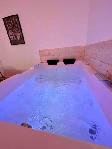 une grande baignoire remplie d'eau bleue dans une pièce dans l'établissement A0 Grand Appartement, Jaccuzi, et extérieur Thermal Artem à 200m, à Nancy