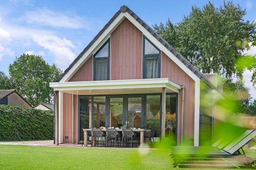 a house with a dining table in front of it at Oude Nieuwelandseweg 33A - Ouddorp - Villa IJsvogel (with jacuzzi, extra costs for use) in Ouddorp