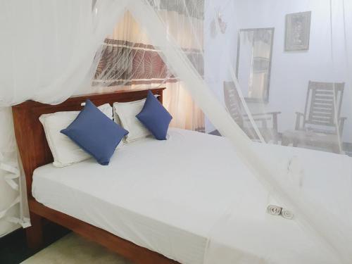 a bed with two blue pillows in a room at SK HOUSE RESORT UNAWATUNA in Unawatuna
