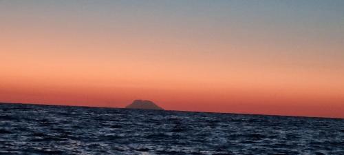 a mountain in the ocean at sunset at Villa Rosetta - Casa Vacanze in Palmi