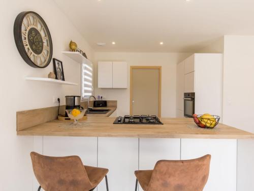 une cuisine avec des placards blancs et une horloge murale dans l'établissement Holiday Home Kervennou by Interhome, à Saint-Jean-du-Doigt