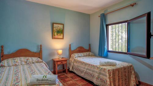 1 dormitorio con 2 camas y ventana en Casa Madrona Periana by Ruralidays, en Periana