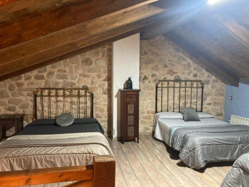2 camas en una habitación con una pared de piedra en Acebos del Tajo, en Peralejos de las Truchas