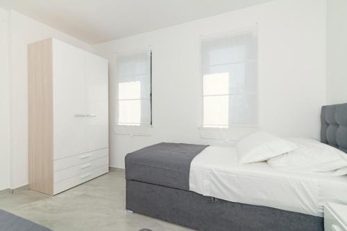 a white bedroom with a bed and a mirror at Kuća za odmor Laura in Biograd na Moru