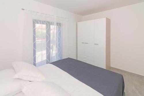 a white bedroom with a bed and a window at Kuća za odmor Laura in Biograd na Moru