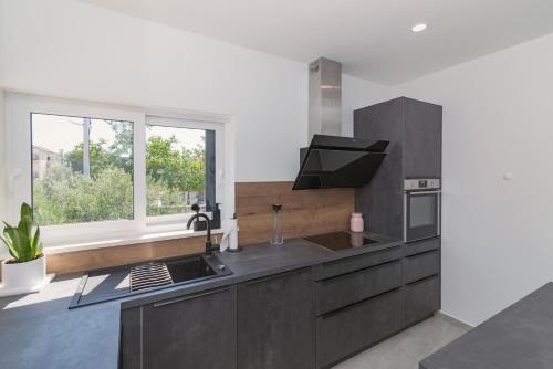 a kitchen with black cabinets and a window at Kuća za odmor Laura in Biograd na Moru