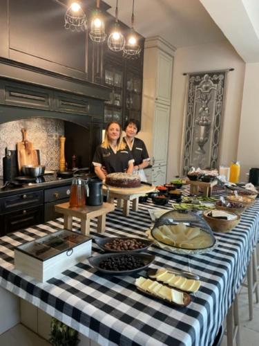 two women standing in a kitchen with a table full of food at Villa Mantilari Wine Estate 7 Apartments 2 Private Pools 1 Heated Tennis Court Fitness Center in Archanes