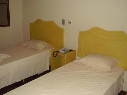 two beds in a small room with a phone on a table at Klinn Hotel in Tanabi