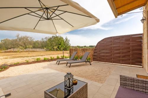 a patio with two chairs and an umbrella at TENUTA DOROLIVO in Otranto
