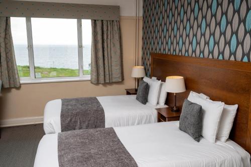 Habitación de hotel con 2 camas y ventana en Commodore Hotel by Greene King Inns en Bournemouth