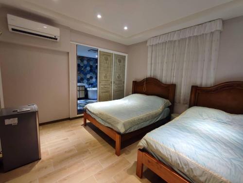 1 dormitorio con 2 camas y ventana en 寶格儷舍, en Anping