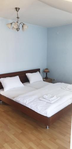 uma cama com lençóis brancos e duas toalhas brancas em GIGA APARTMAN em Jagodina