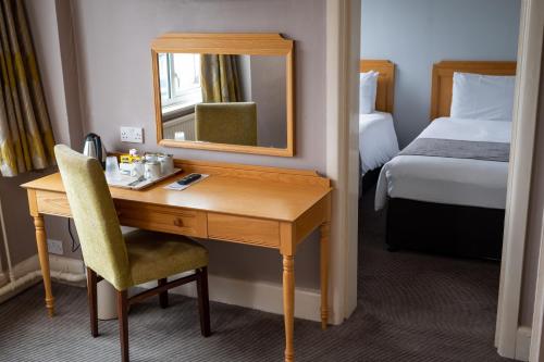 a hotel room with a desk and a mirror at Commodore Hotel by Greene King Inns in Bournemouth