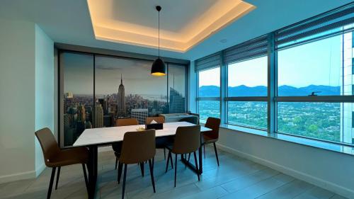 a dining room with a table and chairs and large windows at Centaurus Apartment Mountain View Two Bedroom in Islamabad