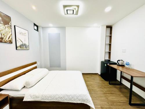 a white bedroom with a bed and a desk at Thai Van Home in Ho Chi Minh City
