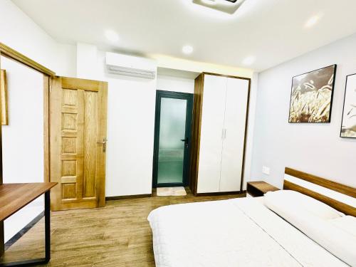 een witte slaapkamer met een bed en een bureau bij Thai Van Home in Ho Chi Minh-stad