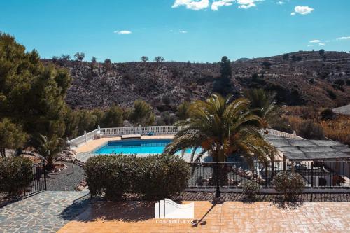 une piscine avec un palmier et une montagne dans l'établissement Hotel Los Sibileys, à Puerto Lumbreras