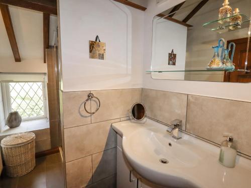 uma casa de banho com um lavatório e um espelho em The Little White Cottage em Llanferres
