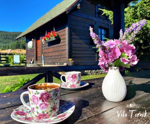 two cups of coffee and a vase of flowers on a table at Vila Tornik in Zlatibor