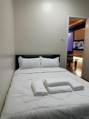 uma cama branca com duas toalhas brancas em The Eden’s Place At San Lorenzo em Manila