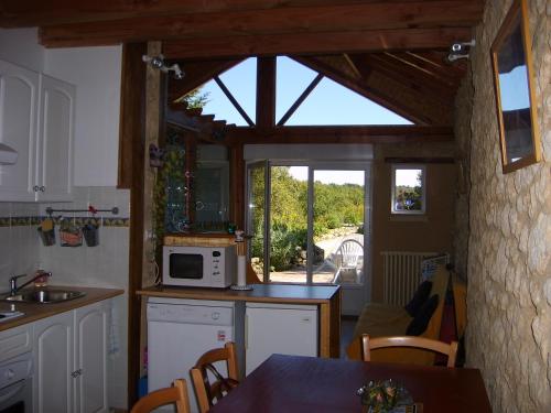 a kitchen with a microwave and a table with chairs at Au lézard doré in Lamonzie-Montastruc