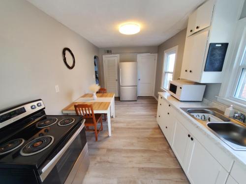 a kitchen with a stove and a sink and a table at Room Near Downtown UofL,Airport&ExpoCenter in Louisville