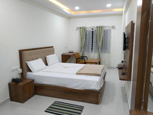 a bedroom with a bed and a television in it at Sambhrama Residency in Shimoga