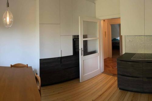 uma cozinha com armários brancos e piso em madeira em Spacious Apartment - green & peaceful em Liubliana