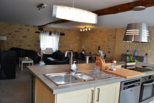 une cuisine avec un évier et un salon dans l'établissement Gîte la Forge 4 étoiles, à Monségur