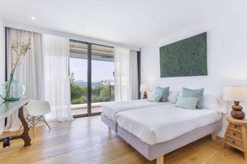 ポルト・ダ・ポリェンサにあるVillas Boquer deluxeの白いベッドルーム(ベッド1台、大きな窓付)