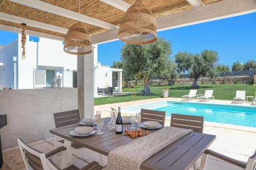 een eettafel en stoelen met een tafel en een zwembad bij TD Villa Patrizia Pool & Alfresco Kitchen in Monopoli