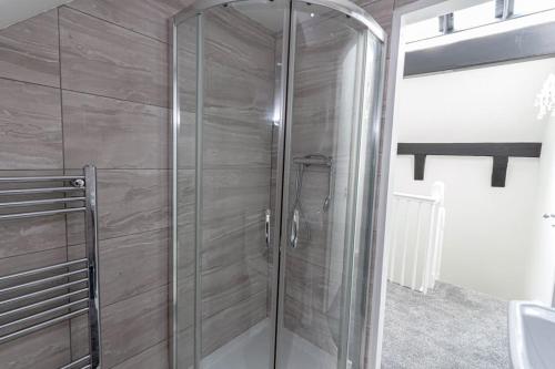 a shower in a bathroom with a glass door at Elegant 1BR Apartment, Sleeps up to 4 in Childwall