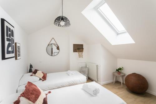 - 2 lits dans une chambre blanche avec lucarnes dans l'établissement Le Saint Martin Bis - Bel appartement moderne et confortable, à Rennes