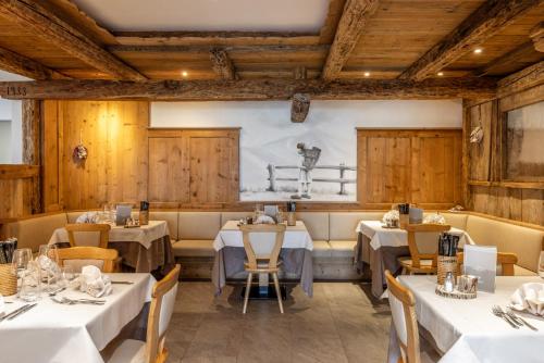 a restaurant with white tables and chairs and wooden walls at Miraval Hotel in Coredo