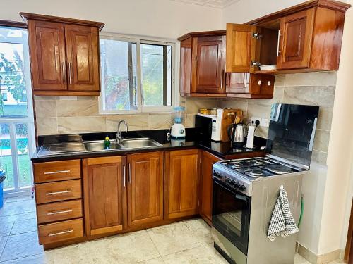 a kitchen with wooden cabinets and a stove top oven at Ocean Oasis 2Br Condo in Dar es Salaam