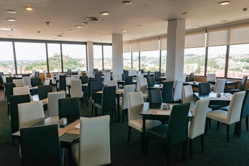 a dining room with tables and chairs and windows at Hotel Eurosol Leiria & Jardim in Leiria