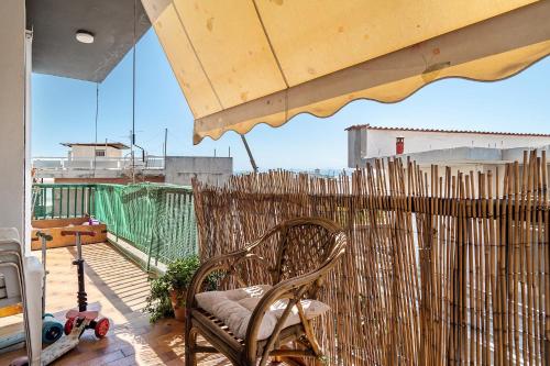 a chair on a balcony with a fence and an umbrella at Nice central family apartment in Gastoúni