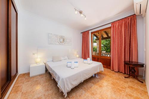 a white bedroom with a bed and a window at Pomeres Nou in Sa Coma